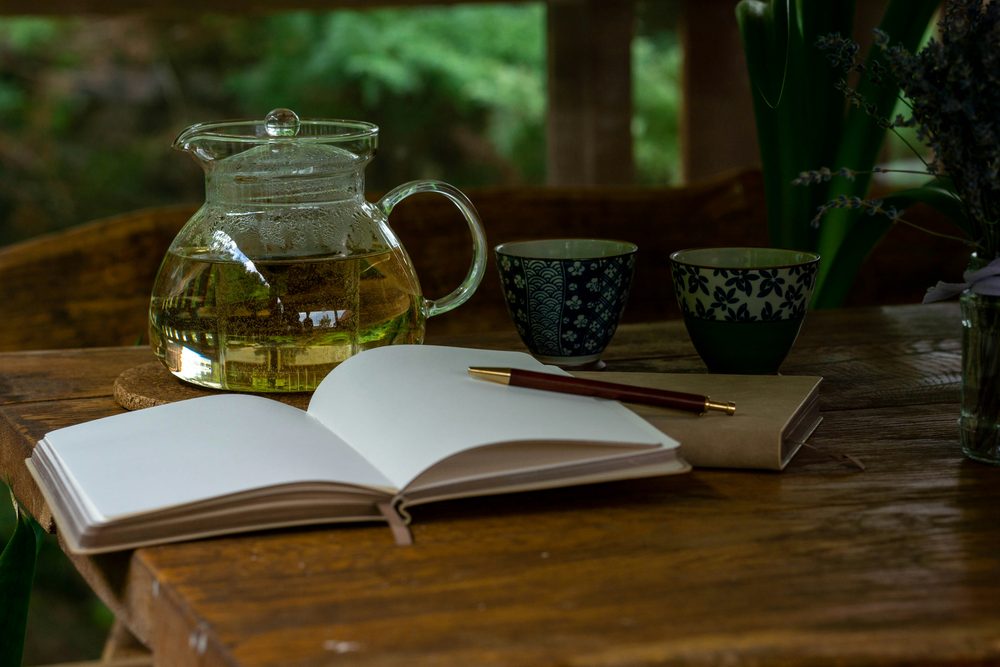 お茶の道具と開いた帳面とペンを置いた机