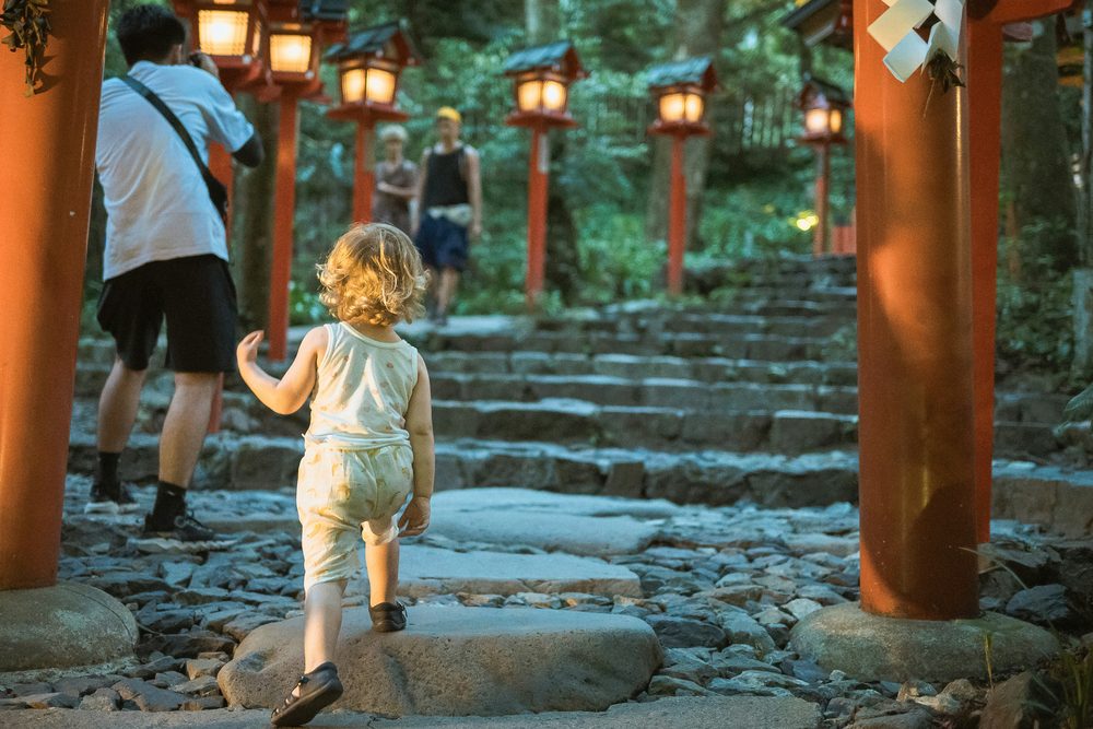 灯籠の並ぶ神社の石段を上る小さな子ども
