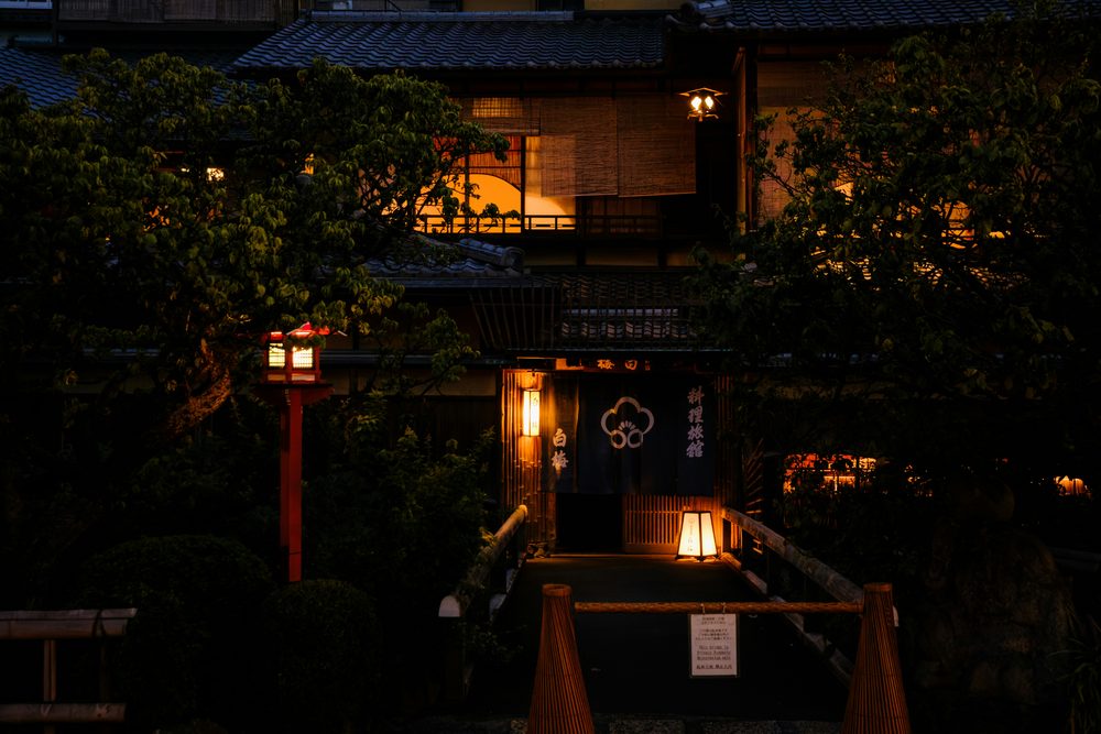 木々に囲まれた夜の宿の入口と灯り