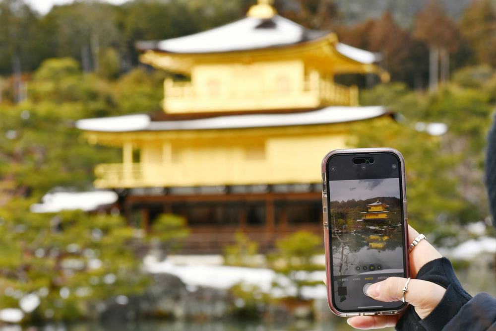 スマートフォンで金閣を写す手元