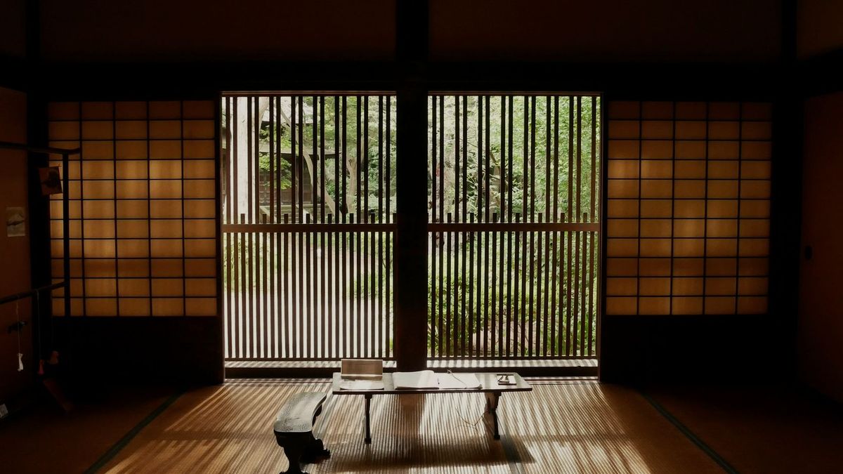 障子を開け放った和室。低い卓の向こうに、明るい庭の緑が見える