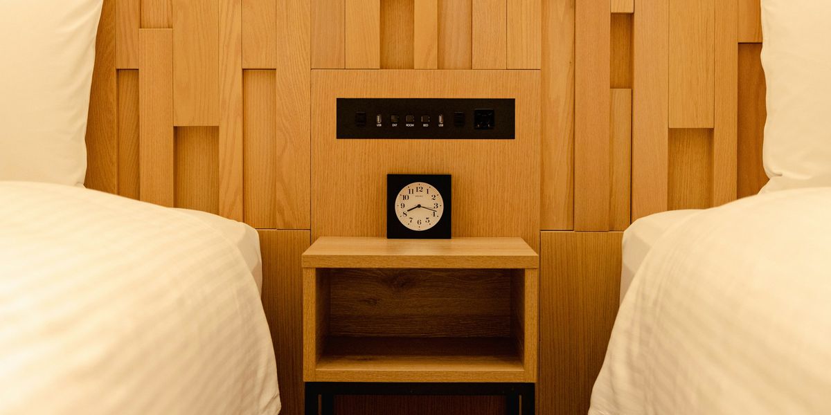 Pale wooden wall panels behind a small wooden bedside table