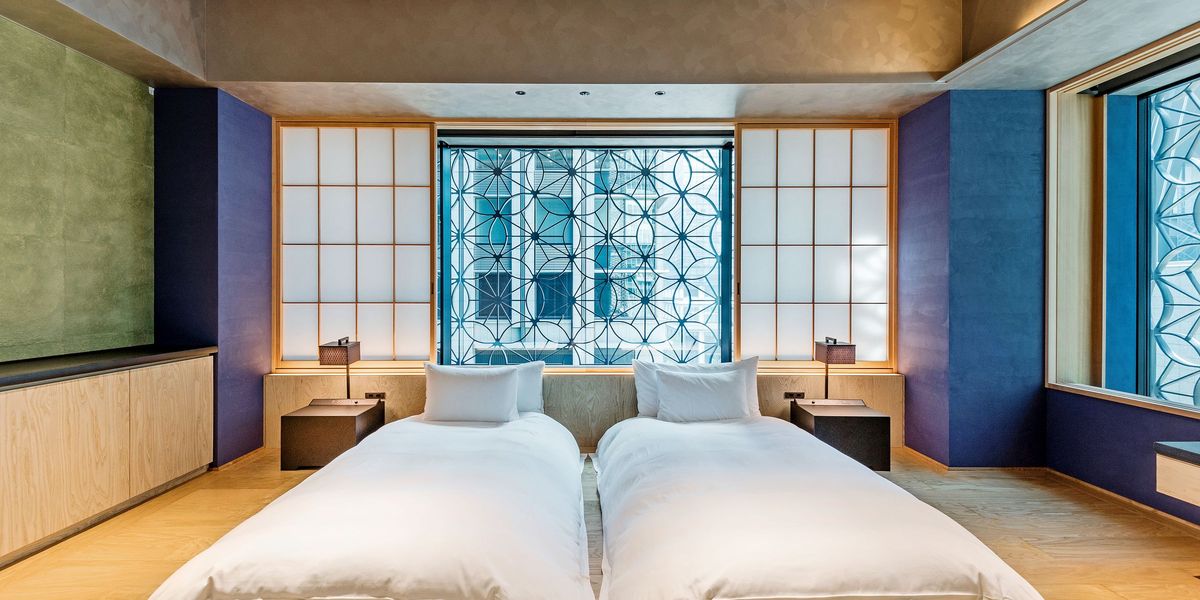A dim bedroom with a low bed and a single wall light
