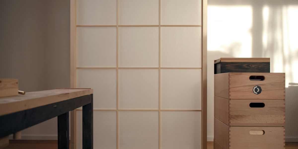 A washi sliding screen in a pale wood frame beside a wooden chest