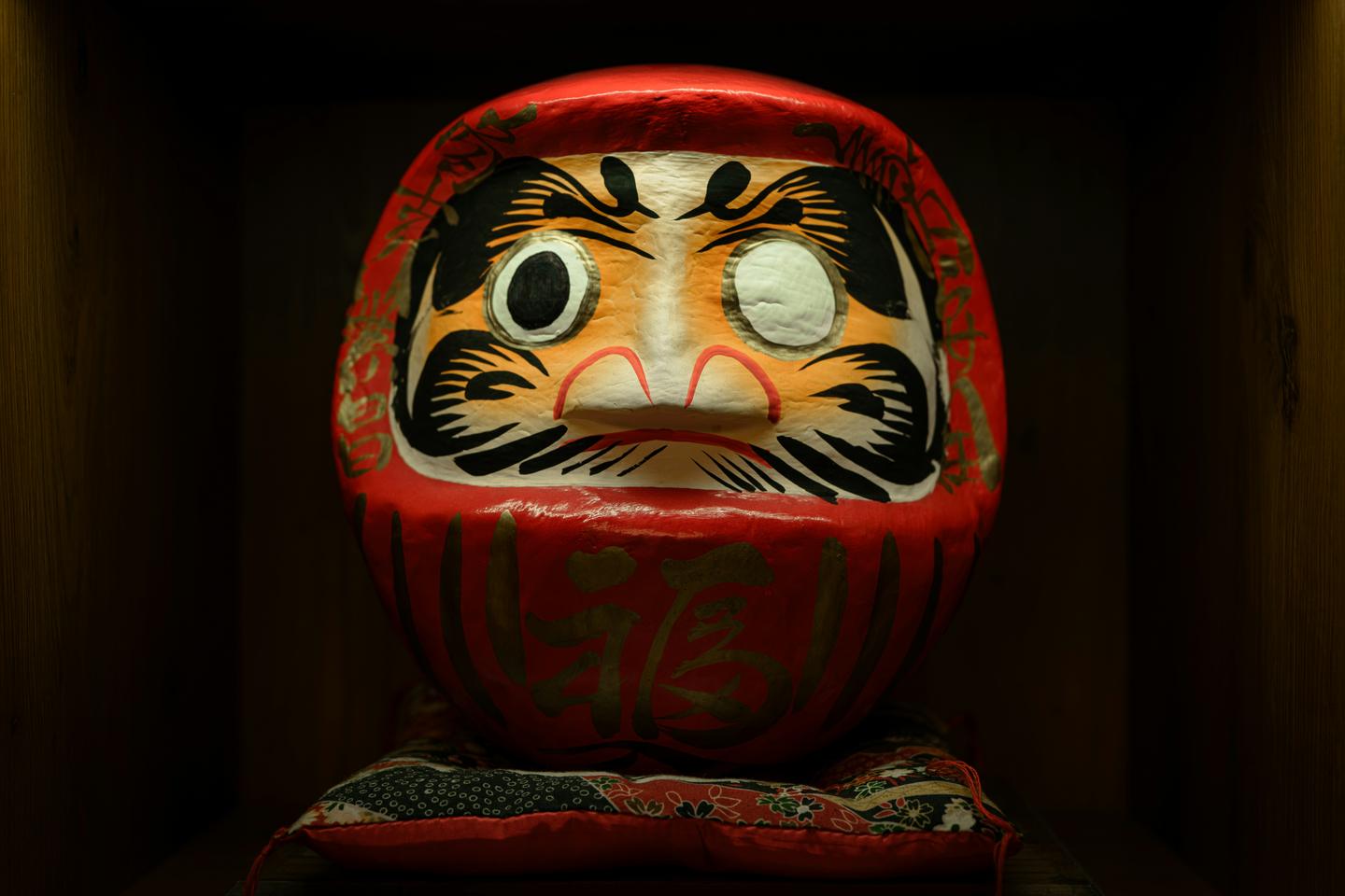 A red daruma with one eye painted in and the other still blank