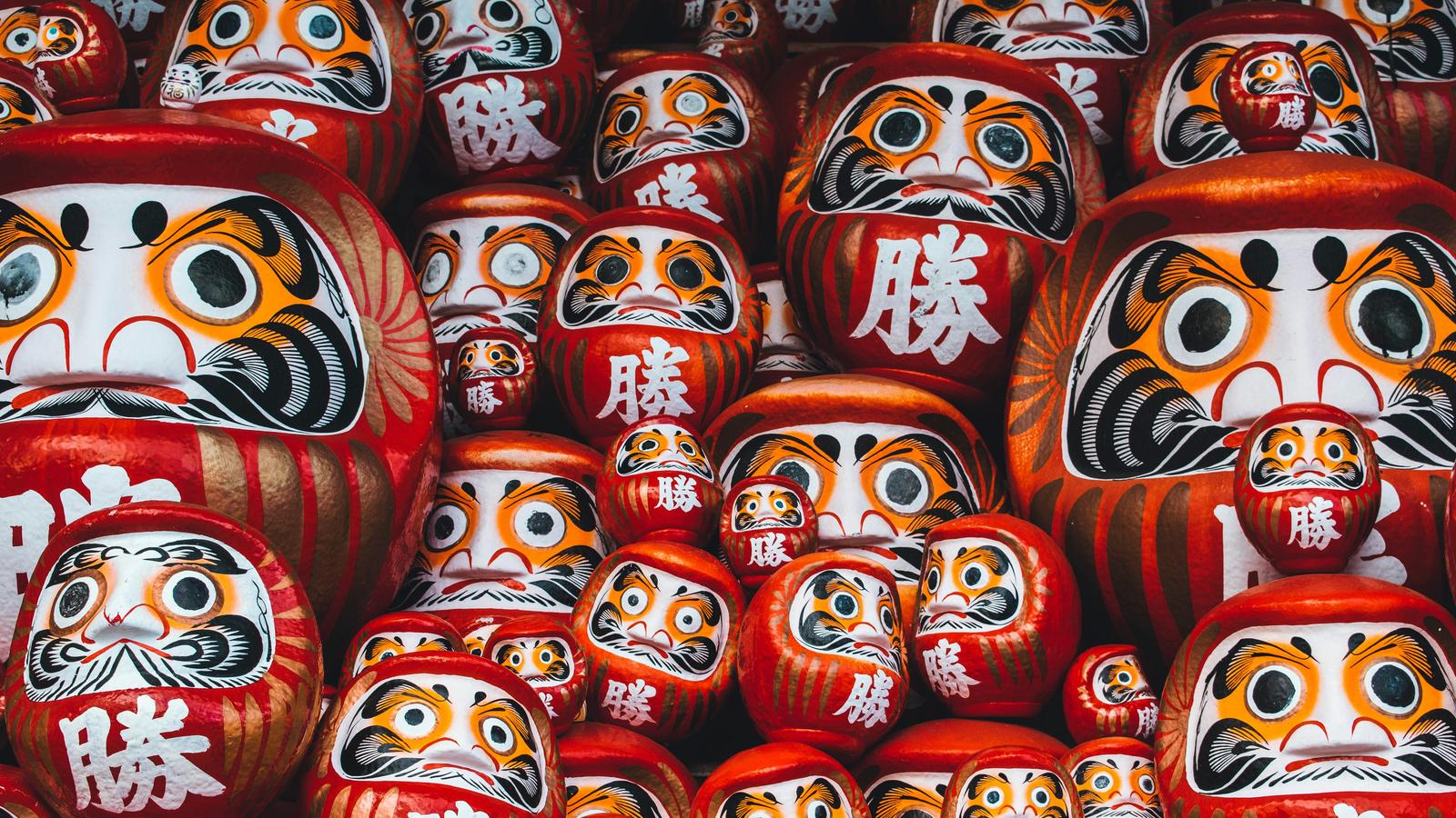 Rows of red daruma dolls with painted faces and the character for victory, at Katsuoji in Minoh