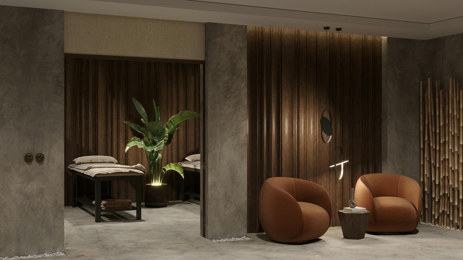 A quiet spa treatment room with a treatment bed, two armchairs and soft lighting