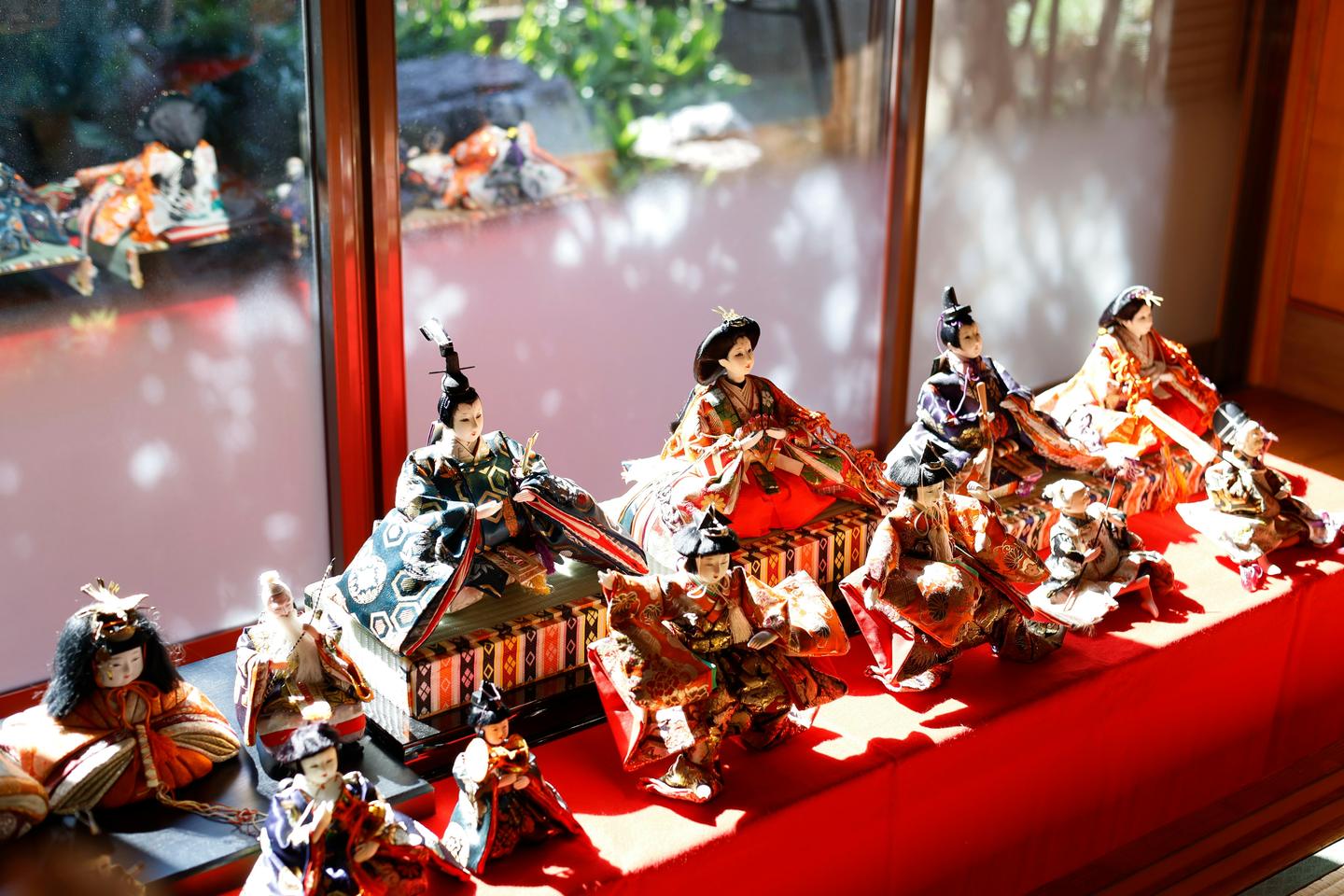 Hina dolls in court robes displayed on red cloth by a window for the March doll festival
