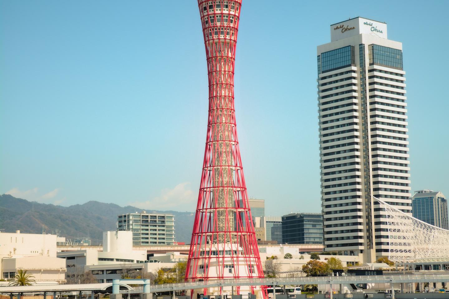 The red lattice of Kobe Port Tower rising above the harbour under a clear sky
