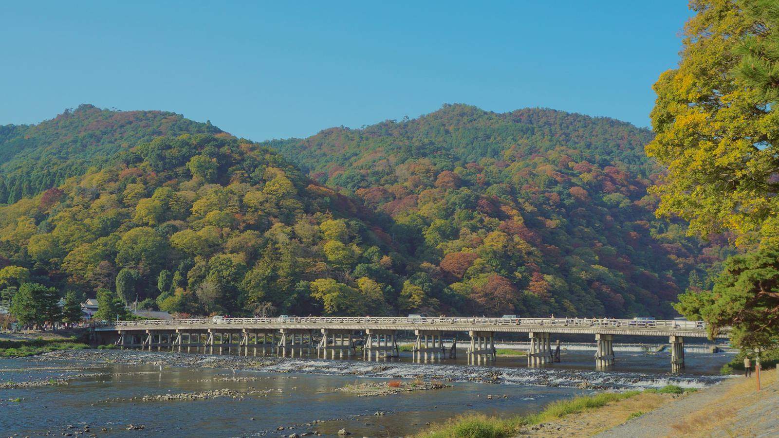 Togetsukyo Bridge in Arashiyama, Kyoto, with the wooded hills turning to autumn colour behind it