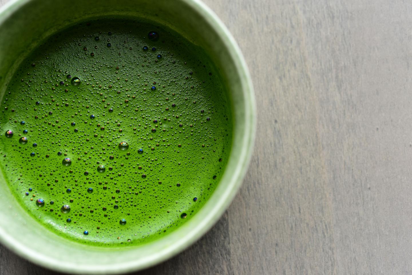 A bowl of whisked matcha seen from above, the surface covered in fine foam
