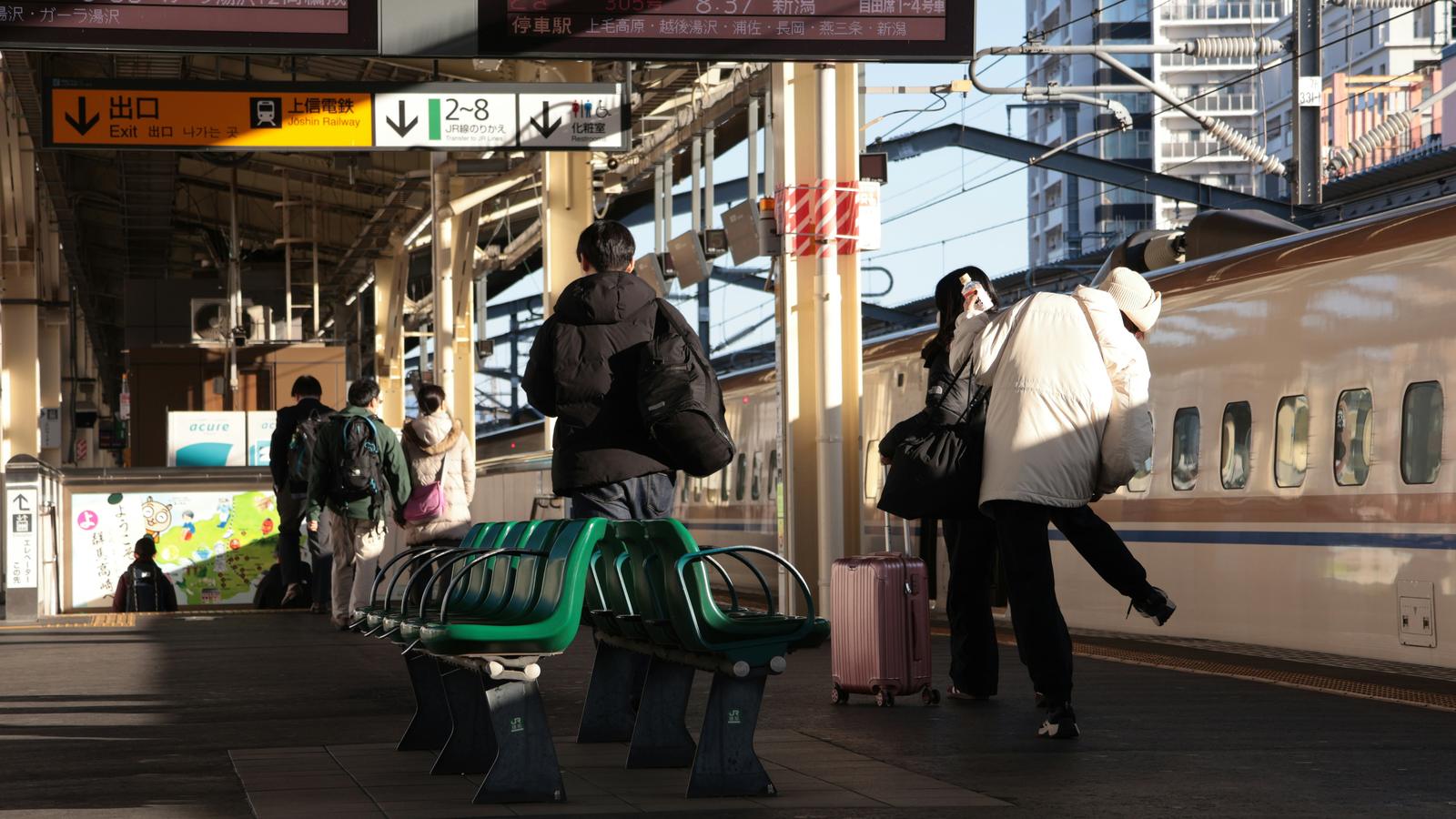 Travellers waiting on a shinkansen platform beside a bullet train at Takasaki Station