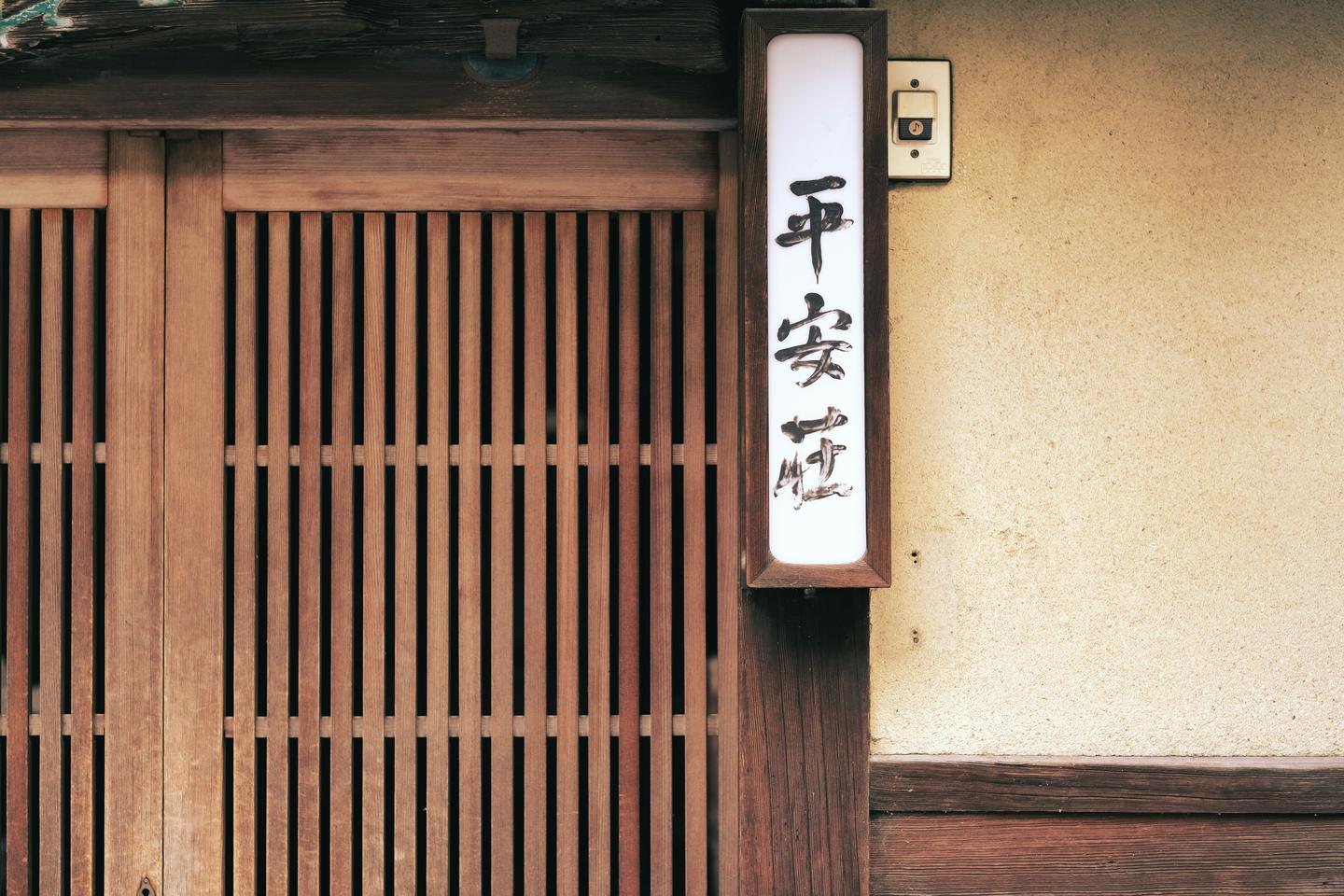 A wooden lattice front in Kyoto beside a white name lantern