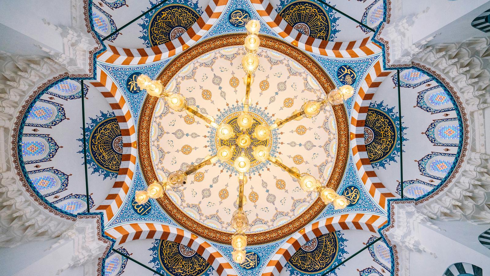 Looking up into the painted dome of Tokyo Camii, with blue and yellow patterns radiating from the centre