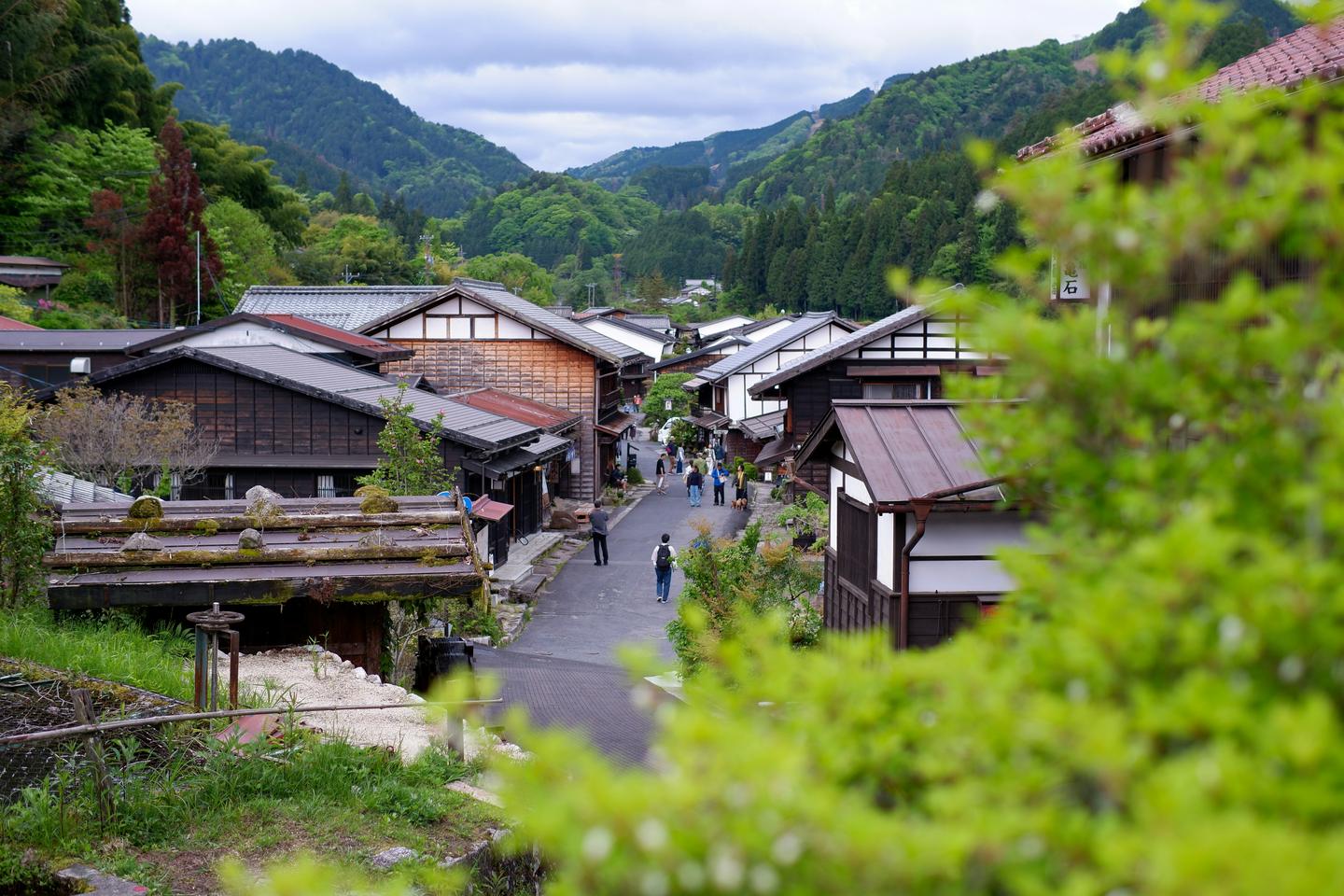 Tsumago's street of wooden houses in a green mountain valley, seen from above