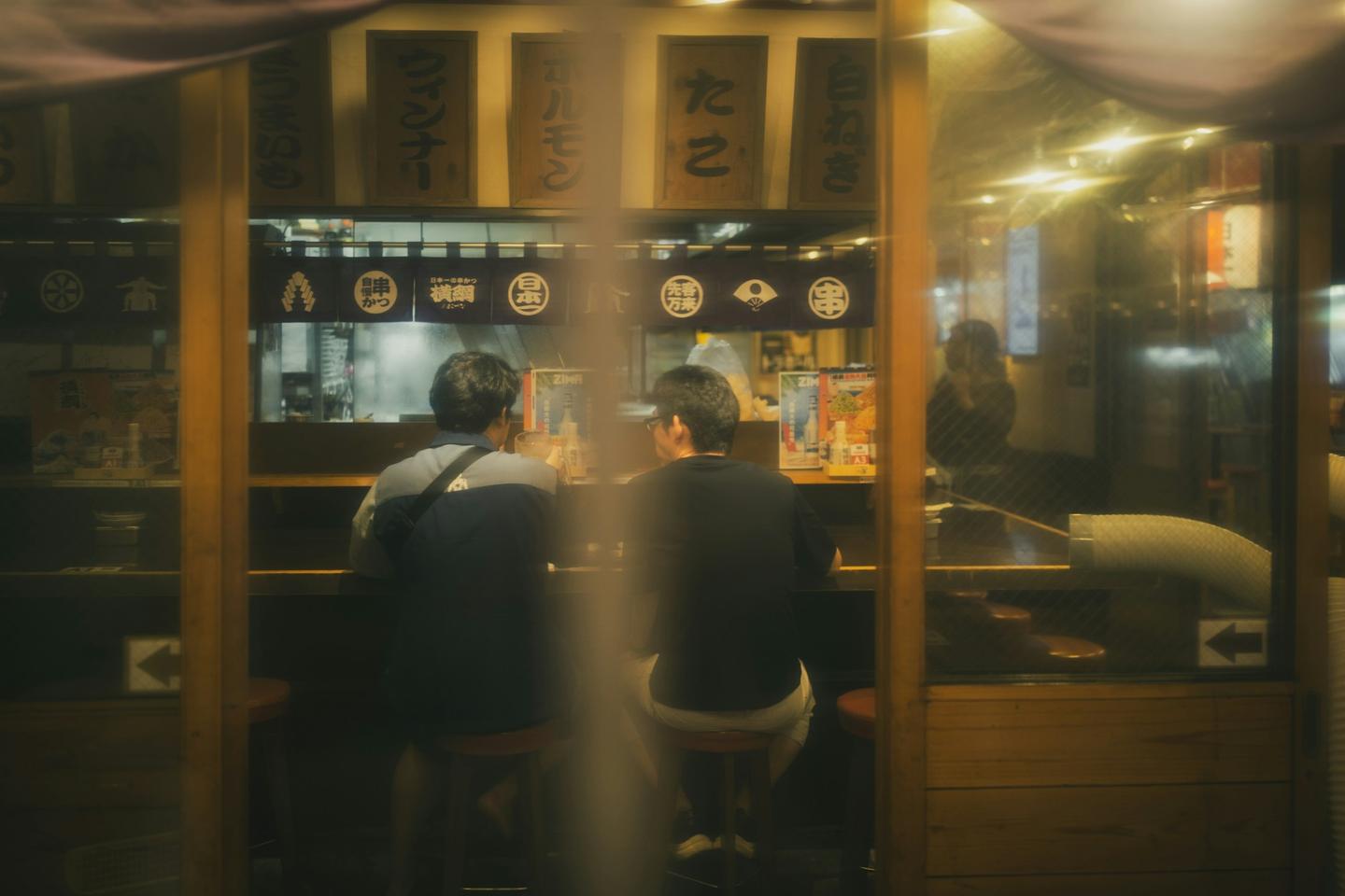 밤에 오사카의 작은 식당 나무 카운터에 앉은 두 손님