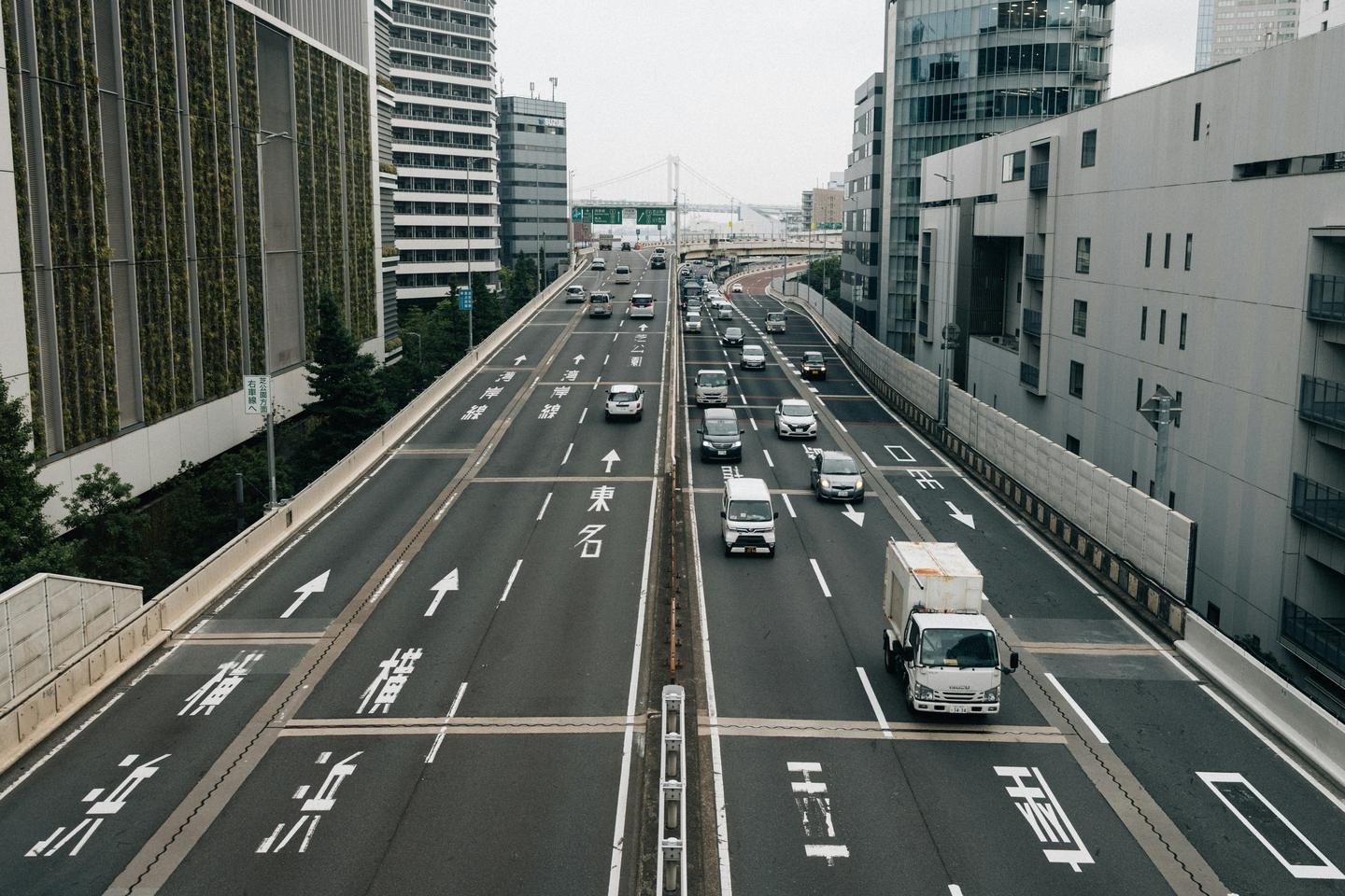 Cars on a multi-lane expressway running between city buildings