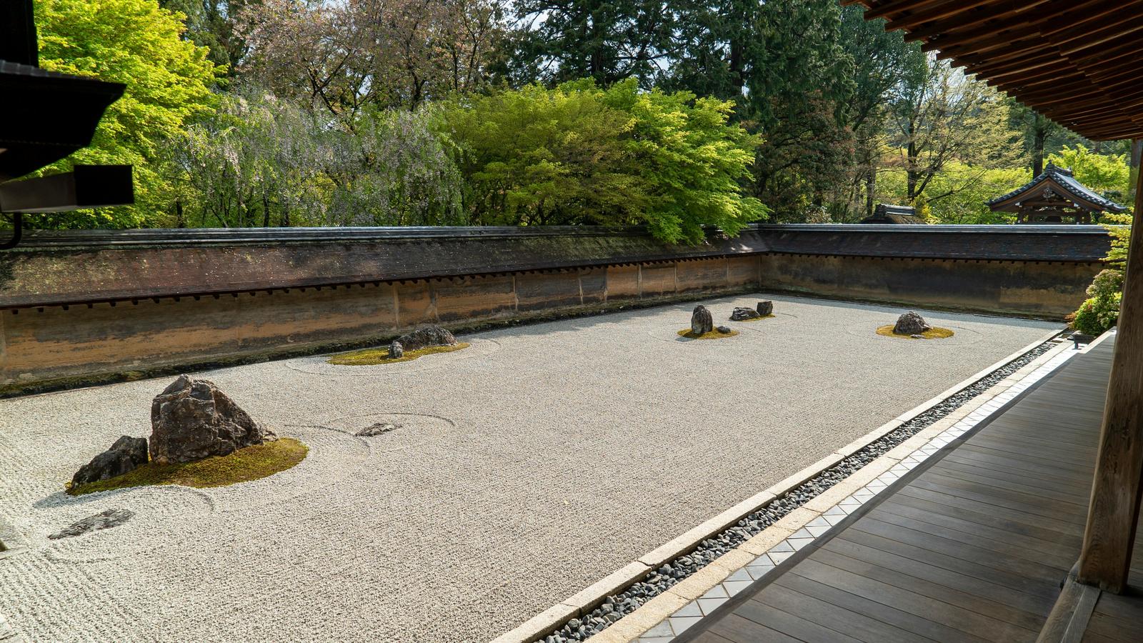 The dry rock garden of Ryoan-ji in Kyoto, raked gravel and stones beside a wooden veranda