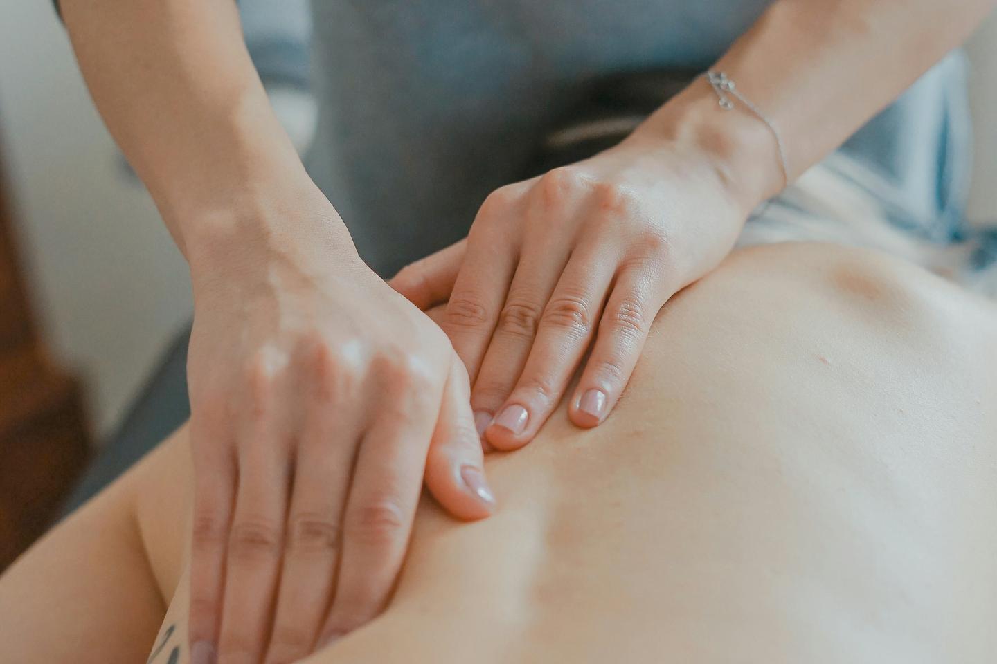 A therapist pressing with both palms on a client's back during a massage