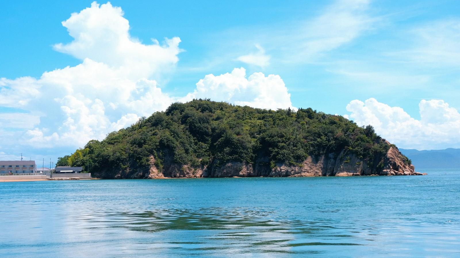 夏日雲層下，直島外海藍色海面上的綠色小島
