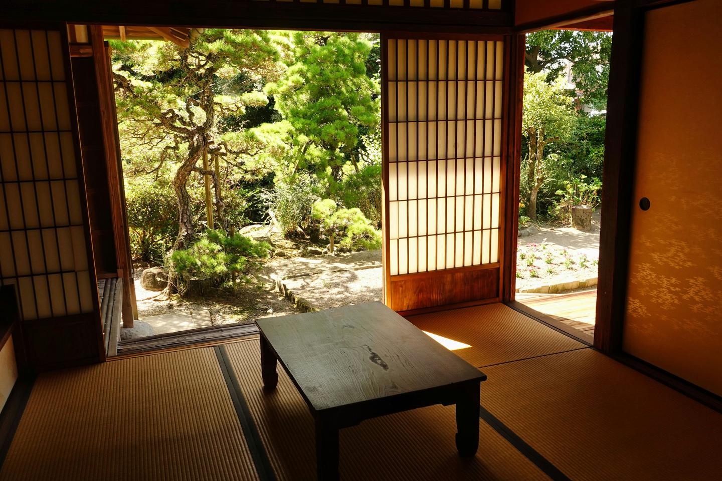 A quiet tatami room with a low table, its sliding doors open onto a garden