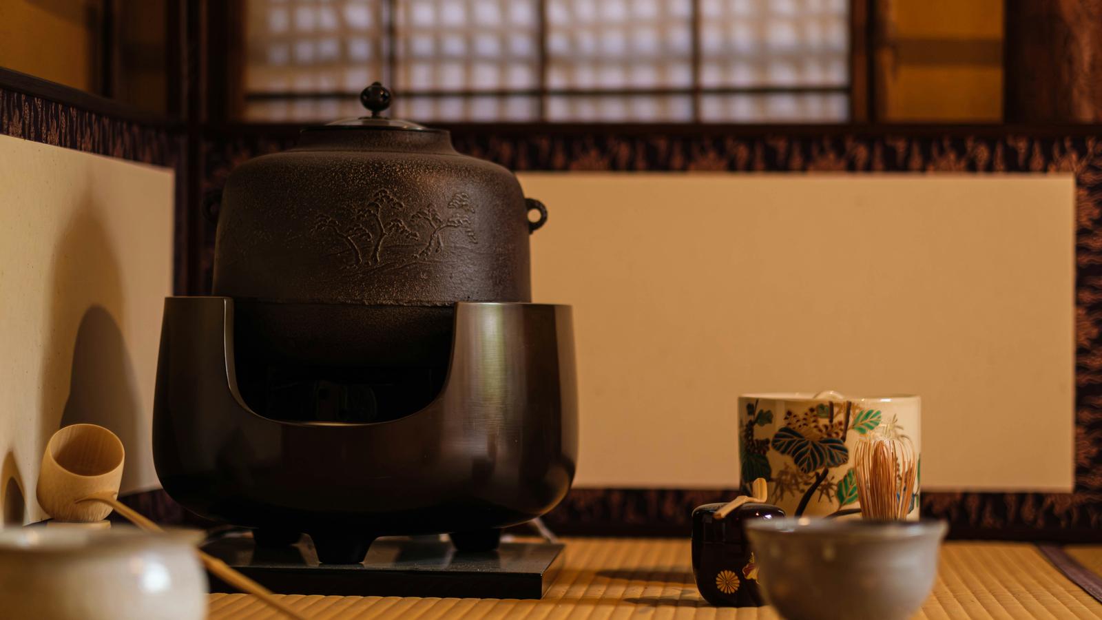 A kettle and tea utensils set out on tatami in a traditional Japanese tea room