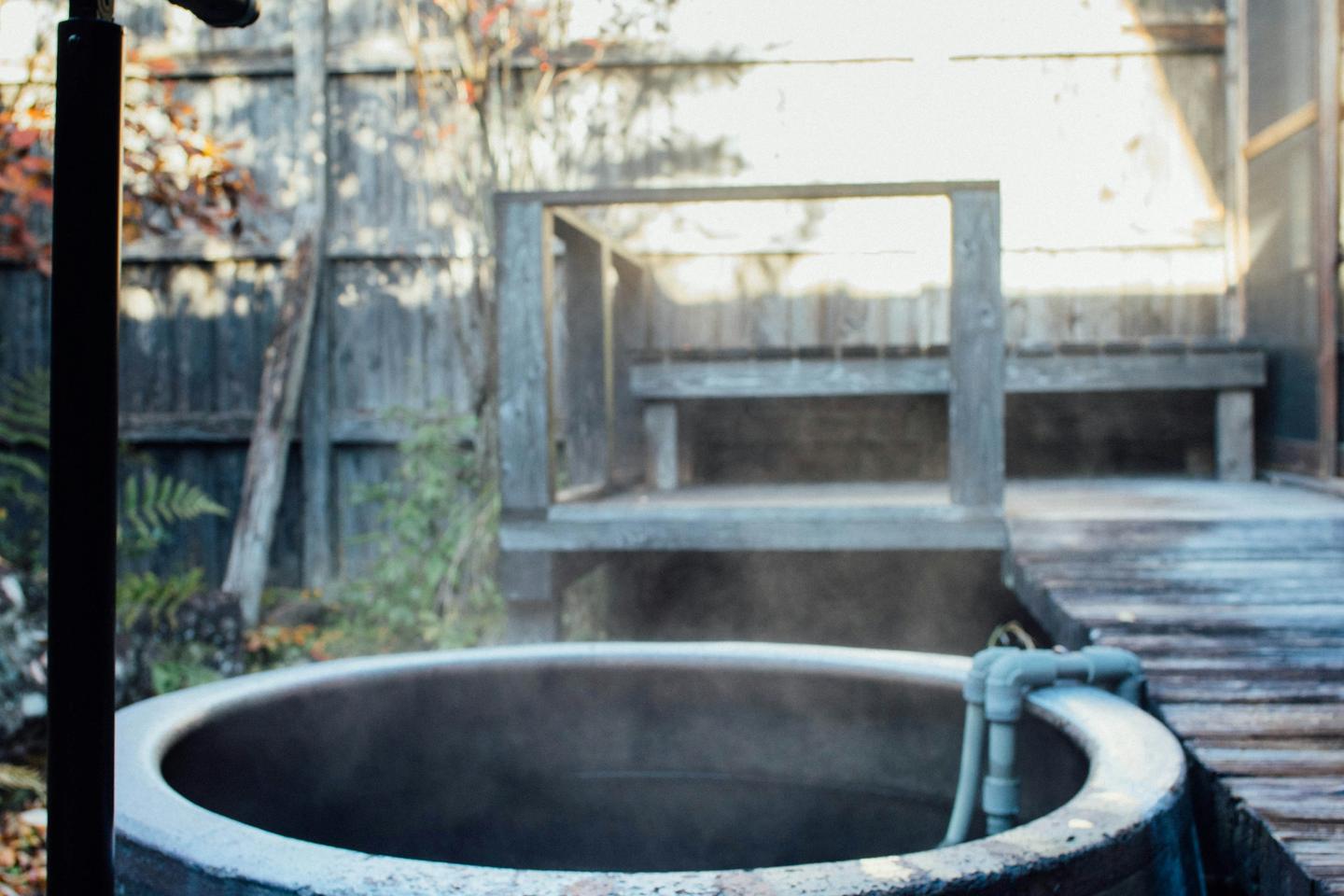 A round outdoor bath on a wooden deck, among autumn trees