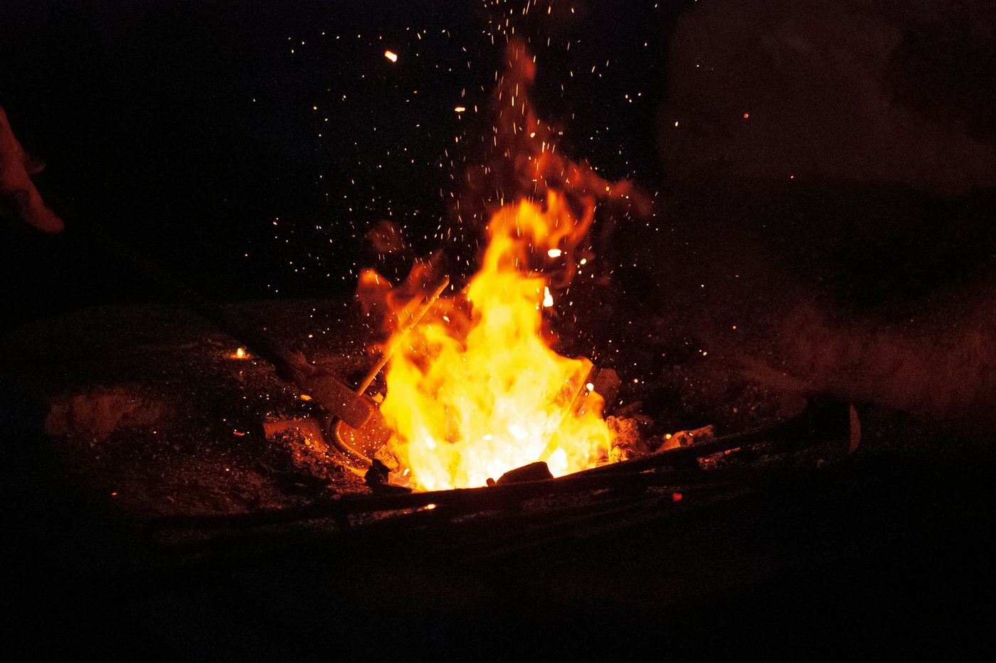 Flames and sparks rising from a charcoal fire at night
