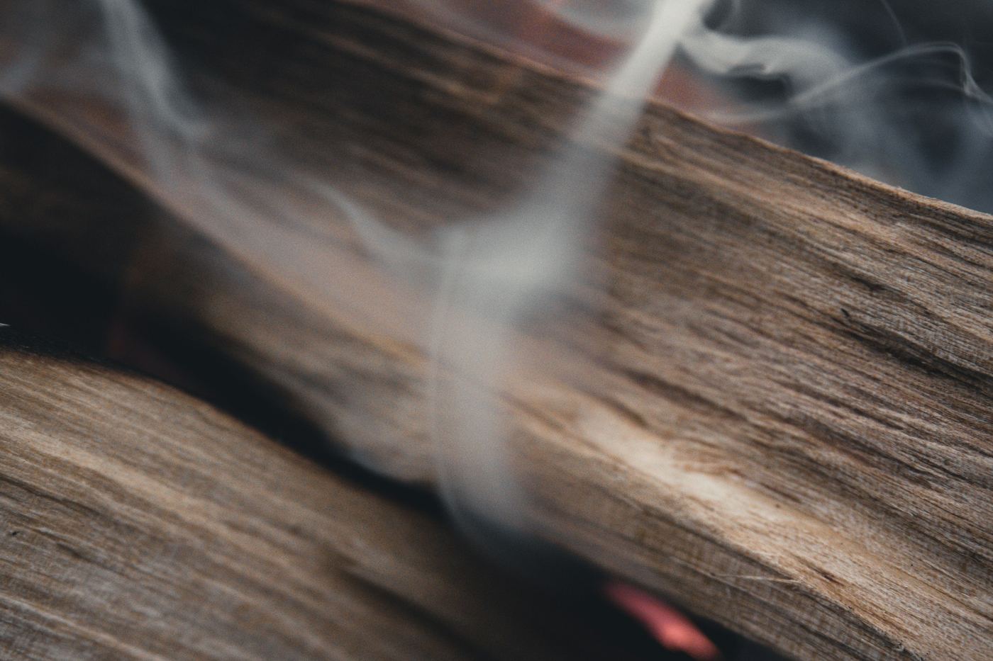 A thin trail of smoke rising from a piece of smouldering wood