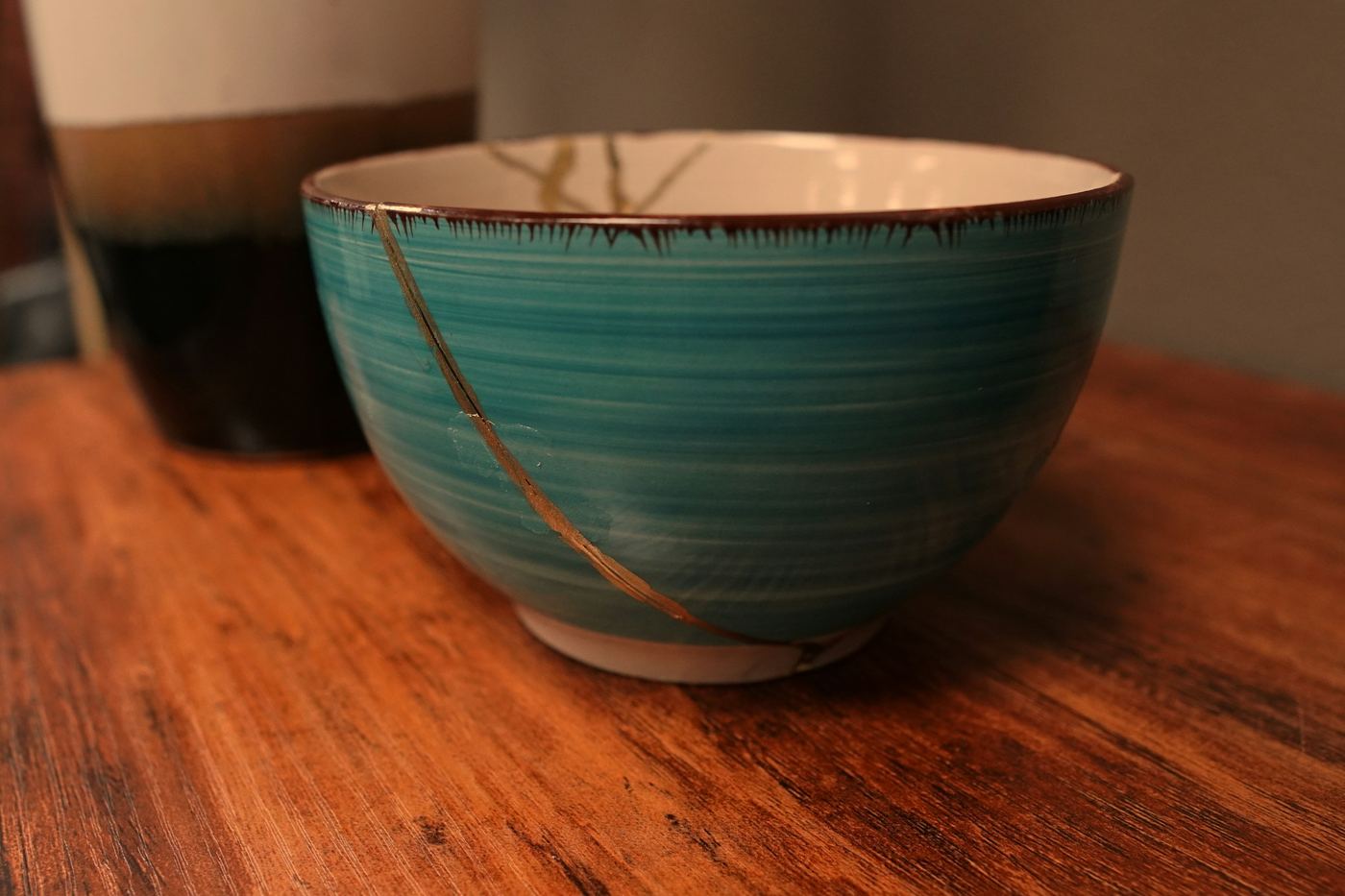 A teal bowl with a thin gold seam on a wooden table