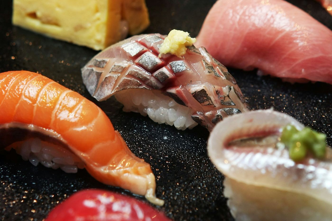 Several pieces of nigiri sushi on a black plate