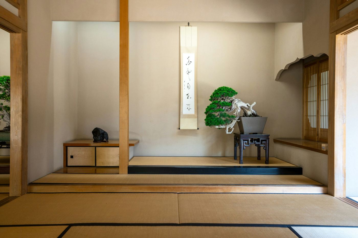 A tatami room with an alcove, a hanging scroll and a small pine