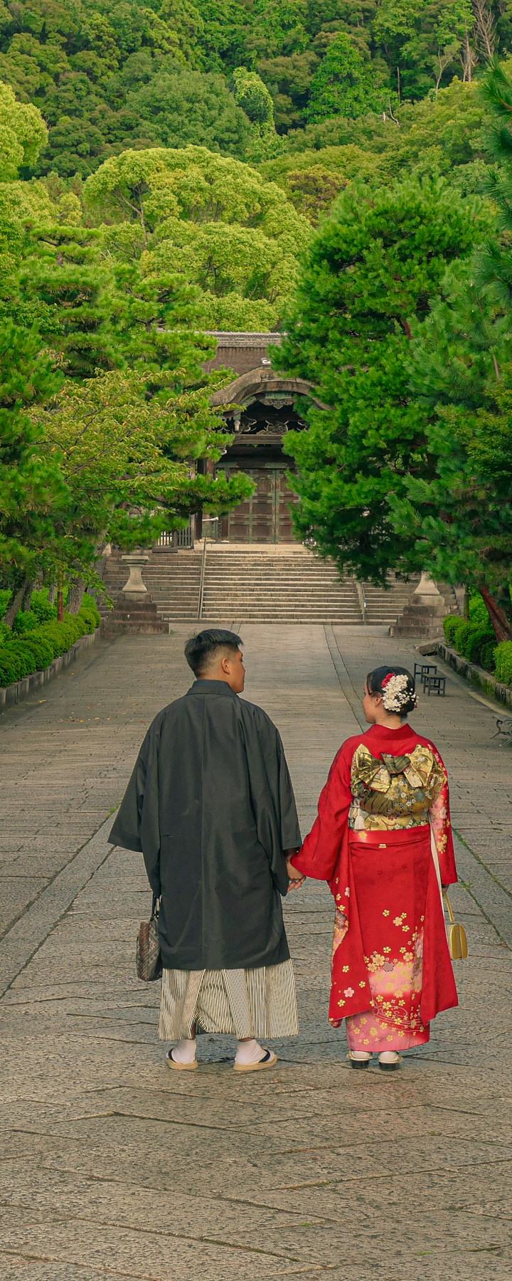 京都のお寺の参道を、着物姿で手をつないで歩く二人