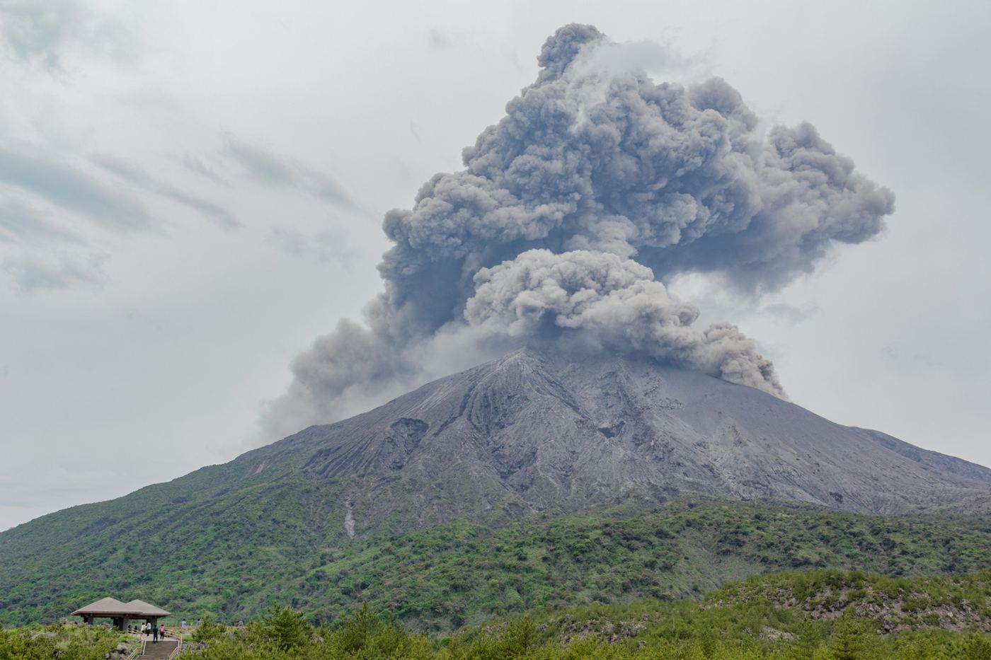 Sakurajima sending a column of ash into a cloudy sky