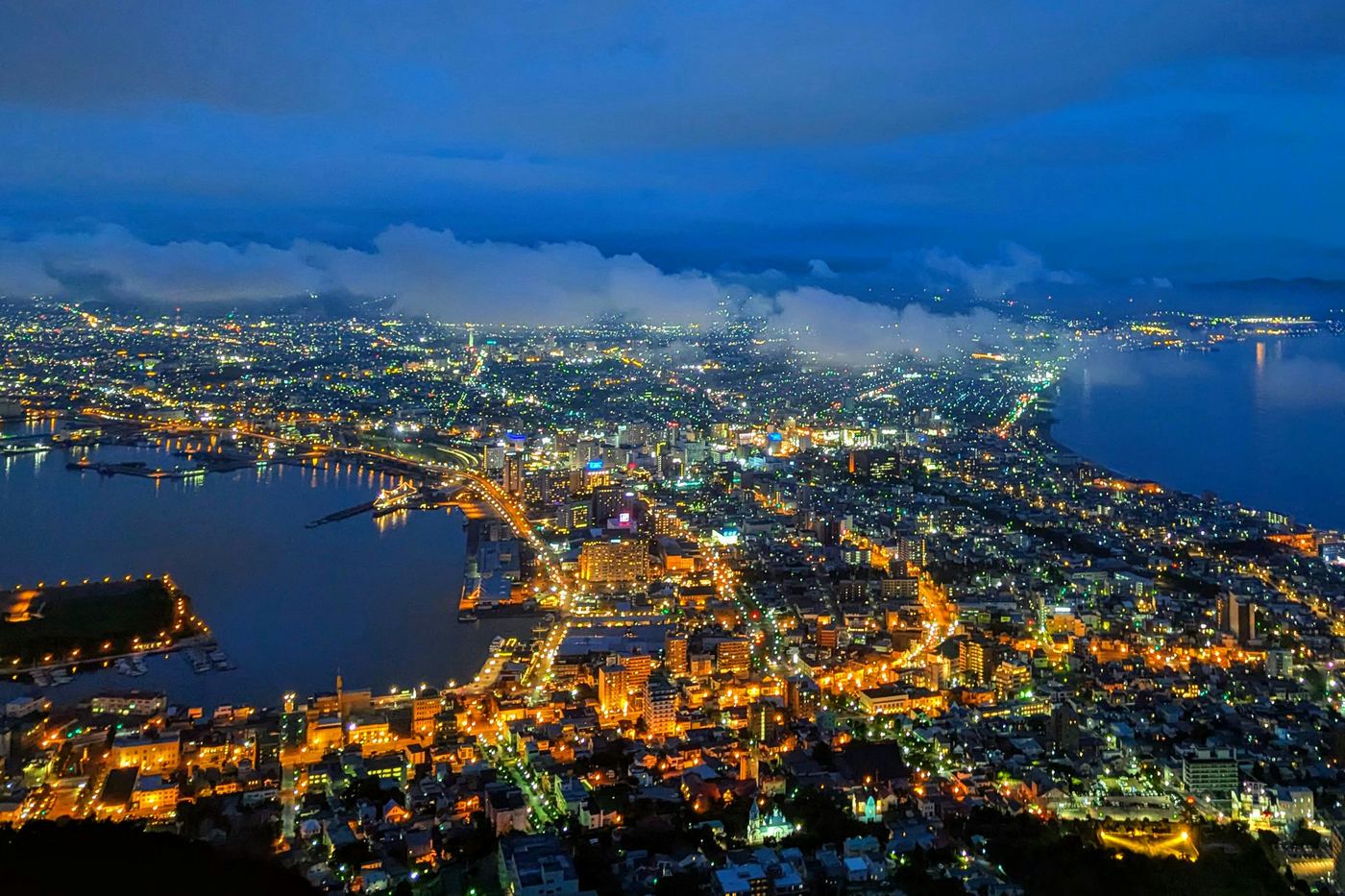 The lights of Hakodate at dusk, spread between two bays, seen from the top of Mount Hakodate
