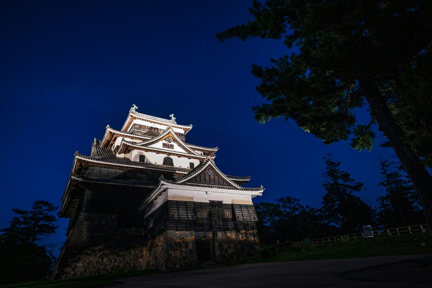 Matsue Castle lit up at night against a deep blue sky
