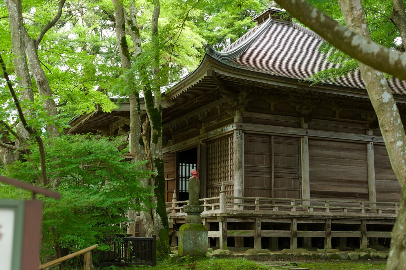 A wooden temple hall among green trees at Chuson-ji in Hiraizumi
