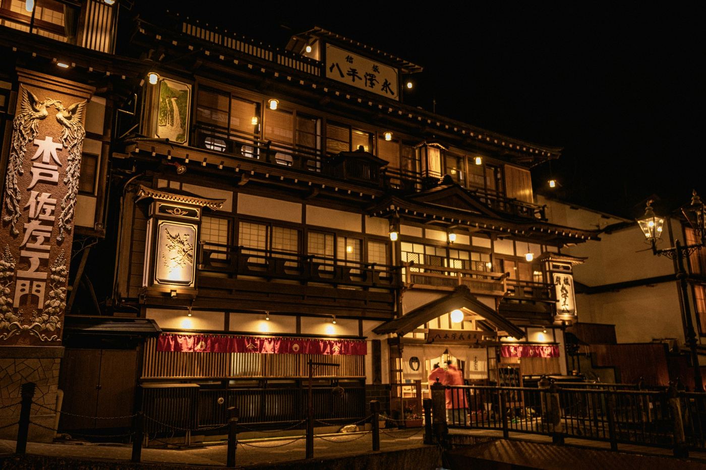 A wooden ryokan at Ginzan Onsen glowing with lamps at night