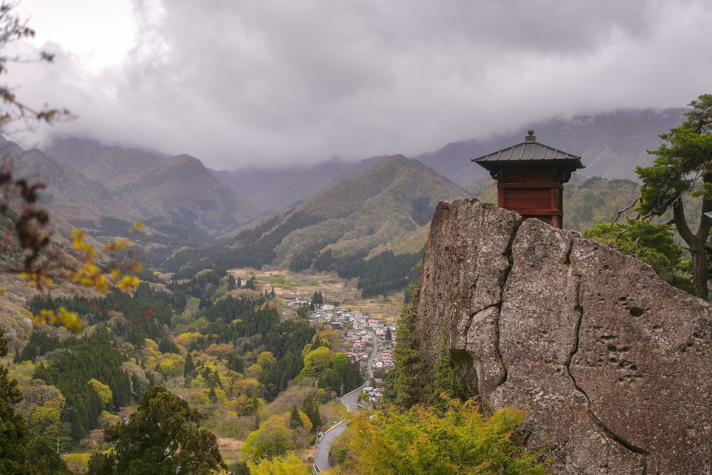 A small temple hall on a rocky outcrop at Yamadera, above a green valley